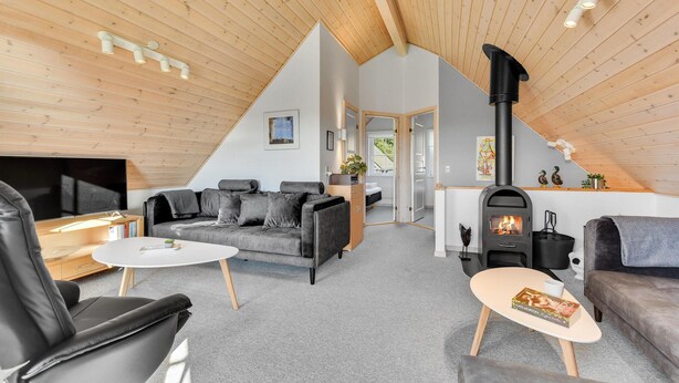 Ein gemütliches Wohnzimmer im Loft-Stil mit hohen Decken, Kamin und Fernseher.