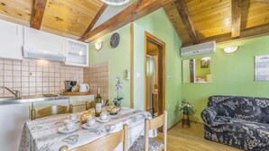A cozy kitchen with a dining table set for four, a sofa, and a wooden ceiling. - Awesome home in Kanfanar with WiFi (Kanfanar)