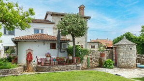 A traditional stone house with a tiled roof, a small garden with a table and chairs, and a stone wall. - Awesome home in Kanfanar with WiFi (Kanfanar)