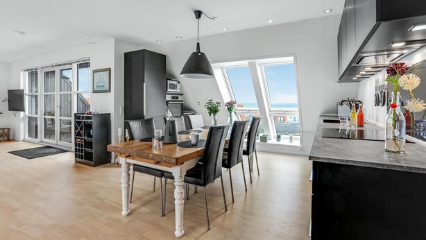 A modern kitchen with a dining area, large windows, and a view of the sea. - Gorgeous apartment in Gudhjem with WiFi (Gudhjem)
