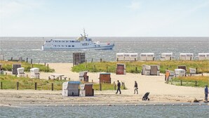 A beach with portable cabins, a boat in the water, and a sandy path.