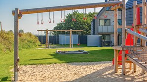 A playground with a sandpit, swings, and a climbing structure.