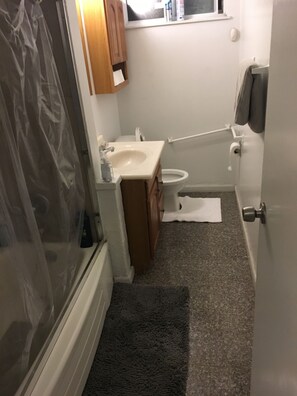 A compact bathroom with a shower, toilet, and sink.
