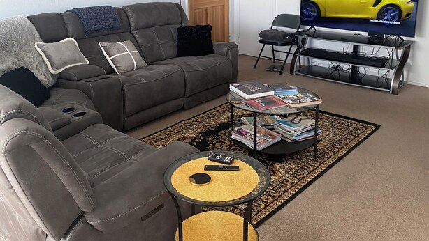 Ein Wohnzimmer mit grauem Sofa, Couchtisch, Fernseher und Bücherregal.