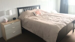 Ein Schlafzimmer mit einem Bett, einem Nachttisch, einer Lampe und einem Wandbild.
