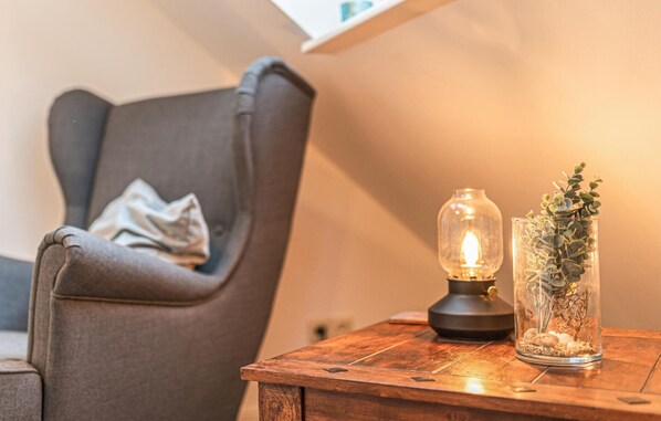 A cozy room with a wooden table, a lamp, and a glass vase with plants.