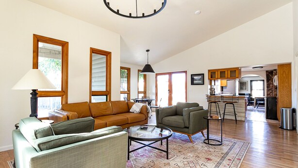A spacious living room with a sofa, armchairs, and a coffee table. There is a kitchen area with a bar and a dining table. - 5-Star Lux Modern Cabin in DT Fruita ❊ Dog Friendly❊ (Fruita)