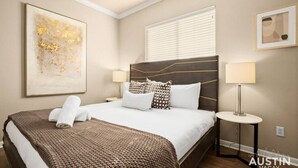 A hotel room with a large bed, a bedside table, a lamp, and a framed picture on the wall. - 8th #B xxxxxxxxxxxxx (Austin)