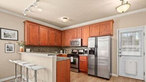 Une cuisine moderne avec des meubles en bois, des appareils électroménagers en acier inoxydable et un coin bar.