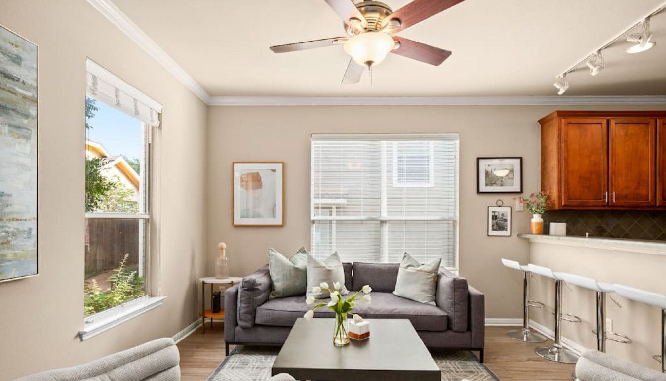 A spacious living room with a gray sofa, a coffee table, and a ceiling fan.
