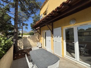 A patio with a table and chairs, a covered area with a pergola, and a sliding glass door leading to an outdoor seating area.