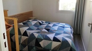 Een slaapkamer met een bed, een houten hoofdbord en een raam met gordijnen.