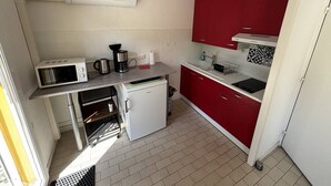 Een kleine keuken met een magnetron, koffiezetapparaat en een koelkastje.