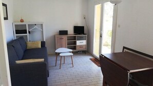 Een knus woongedeelte met een bank, een tafeltje, een televisie en een kast.