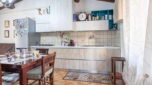 Cozinha com teto de madeira, armários brancos, painel de azulejos e um relógio na parede.
