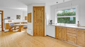 Eine moderne Küche mit Holzausstattung, einem großen Fenster und einer Essecke mit einer Bank.