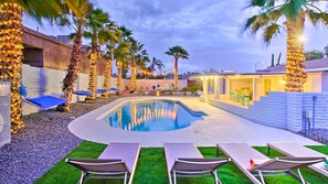A pool area with lounge chairs, palm trees, and a covered seating area. - Heated Pool · Game Room · Resort-Style Yard (Phoenix)