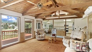 A spacious living room with a high ceiling, large windows, and a view of the mountains.