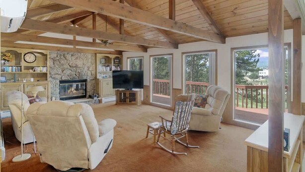 A spacious living room with a stone fireplace, a television, and comfortable seating.