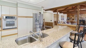 A modern kitchen with granite countertops, stainless steel appliances, and a bar area with seating.