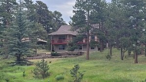 A two-story house with a red roof, surrounded by a grassy area and several trees.