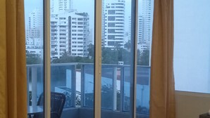 Une chambre dotée d’une grande porte-fenêtre coulissante donnant sur un balcon, d’une petite table avec une chaise et d’un lit.