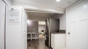 A compact kitchen with a stainless steel refrigerator, white cabinetry, and a wooden floor. - Beautiful Downtown Tacoma Home Unit 2 (Tacoma)
