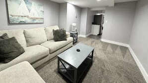 A living room with a sofa, a coffee table, a painting, and a kitchen area in the background. - Beautiful Downtown Tacoma Home Unit 2 (Tacoma)