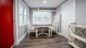 A room with a red door, a white table with two chairs, a window with blinds, and a white console table. - Beautiful Downtown Tacoma Home Unit 2 (Tacoma)