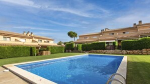 A rectangular swimming pool with a ladder on one side, surrounded by a well-maintained lawn and a row of houses in the background. - Tramuntana by Interhome (L'Escala)