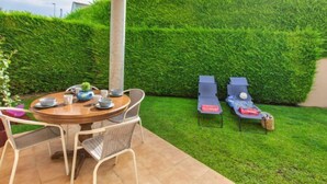 A patio area with a round table and chairs, a tall column, and a neatly trimmed hedge. - Tramuntana by Interhome (L'Escala)