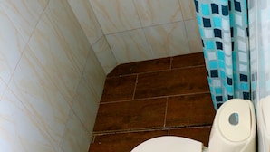 A bathroom with a toilet, a shower curtain, and a tiled floor. - 1C19 Apartamento Cartagena frente al mar (Cartagena)
