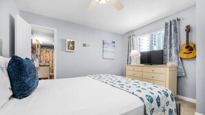 Une chambre à coucher avec un lit, une commode, une guitare et une fenêtre avec des rideaux.