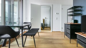 Une cuisine moderne avec un coin repas, un plancher en bois et une vue dégagée grâce à de grandes fenêtres.