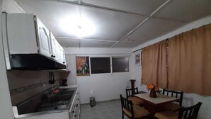 Une cuisine de taille réduite avec des meubles blancs, une cuisinière et une table à manger avec des chaises.