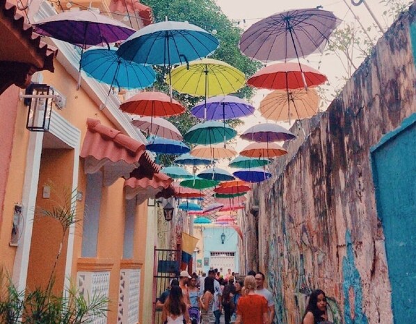 A narrow alley with colorful umbrellas hanging overhead.