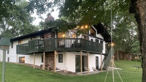 Ein zweistöckiges Haus mit Steinfundament, Holz-Balkonläuten und einem Hängesessel.