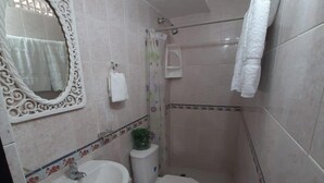 A compact bathroom with a white sink, toilet, and shower. A decorative mirror and a small plant are visible. - 1G3-2 Apartamento en la Ciudad Antigua (Cartagena)