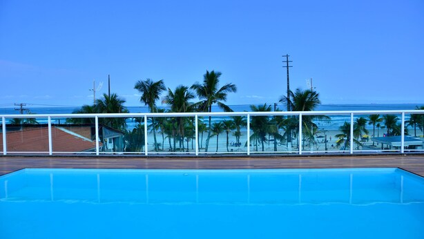 Une piscine avec vue sur une plage et des palmiers.