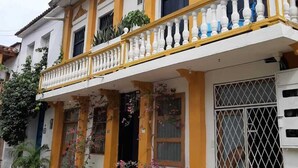 A two-story building with a balcony, potted plants, and a gated window. - 1G2-3 Apartamento en la ciudad Antigua (Cartagena)