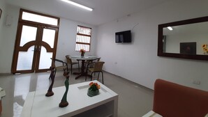 A room with a dining table, chairs, a TV mounted on the wall, and a large mirror. - 1G2-3 Apartamento en la ciudad Antigua (Cartagena)