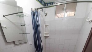 Un baño con inodoro, lavamanos, ducha y espejo.