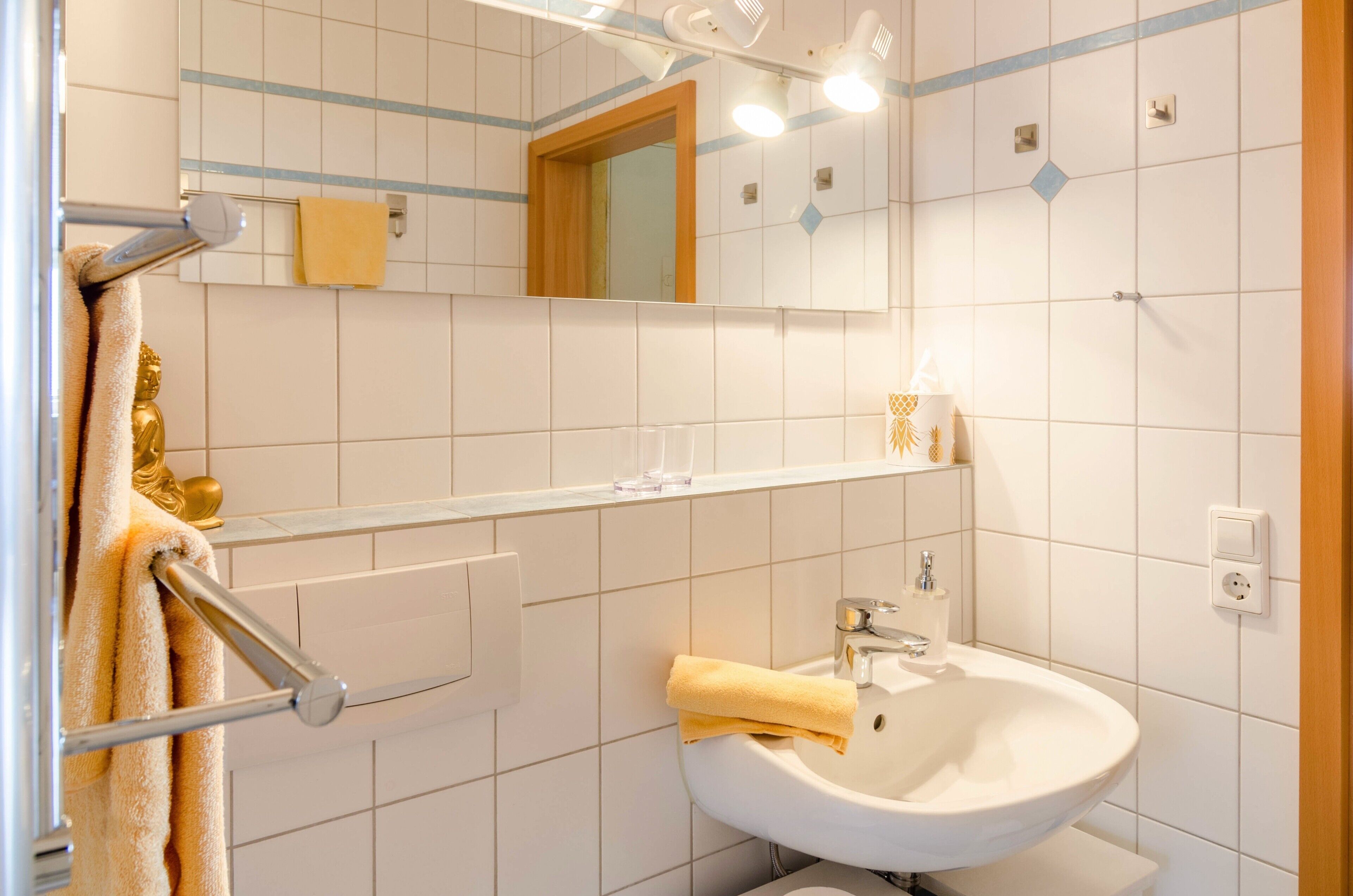 Een badkamer met een wastafel, spiegel, handdoekhouder en toilet.