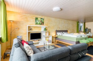Une chambre d’hôtel moderne équipée d’un lit, d’un canapé, d’une télévision et ornée d’un tableau au mur.