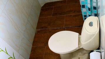 Un baño con inodoro, cortina de ducha y lavamanos.