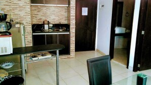 A compact kitchen with a microwave, toaster, and kettle, a dining table with chairs, and a tiled floor. - 2C19 Apartamento Cartagena frente al mar (Cartagena)