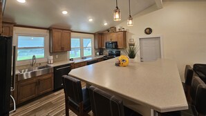 A modern kitchen with wooden cabinets, a large island, stainless steel appliances, and pendant lighting. - Packer themed, renovated 3 bedroom, 2 1/2 bath home- Lambeau Field 16 min walk. (Green Bay)