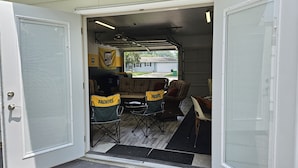 A garage with a table and chairs, a flag, and a door. - Packer themed, renovated 3 bedroom, 2 1/2 bath home- Lambeau Field 16 min walk. (Green Bay)