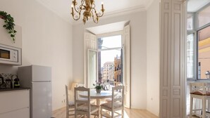A modern kitchen with a dining area, a chandelier, and a view of the city through large windows. - Bright apartment with views of the Cathedral (Málaga)