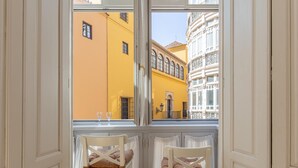 A room with two white chairs with brown cushions, a window with a view of yellow and white buildings. - Bright apartment with views of the Cathedral (Málaga)